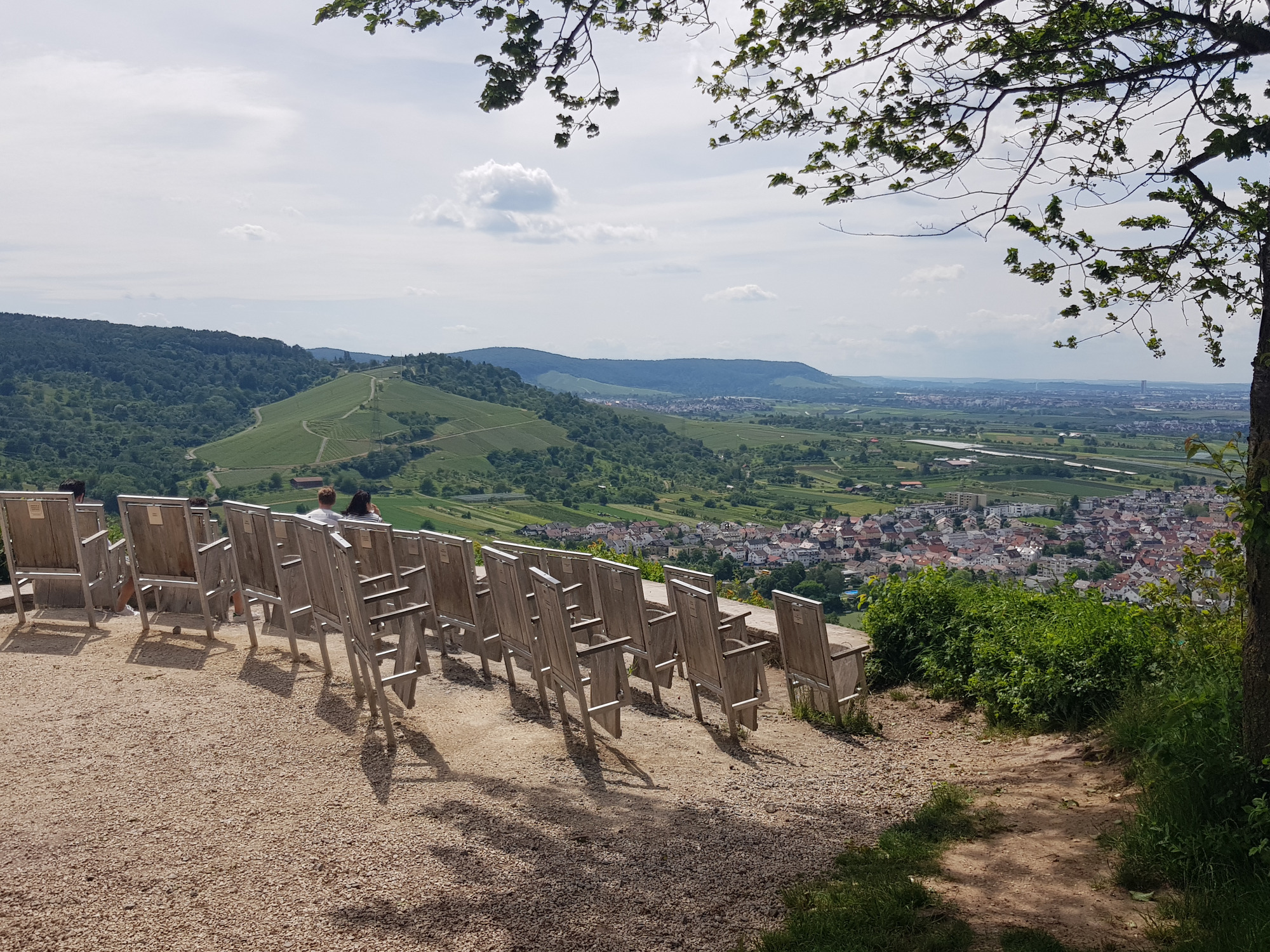 Aussicht vom Remstalkino mit Felsen im Vordergrund, grünen Hügeln, Tal mit Ortschaft und teils bewölktem Himmel.